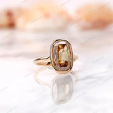 Angled view of champagne moissanite elongated cushion bezel ring.