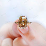 Close-up shot of elongated champagne moissanite ring on finger.