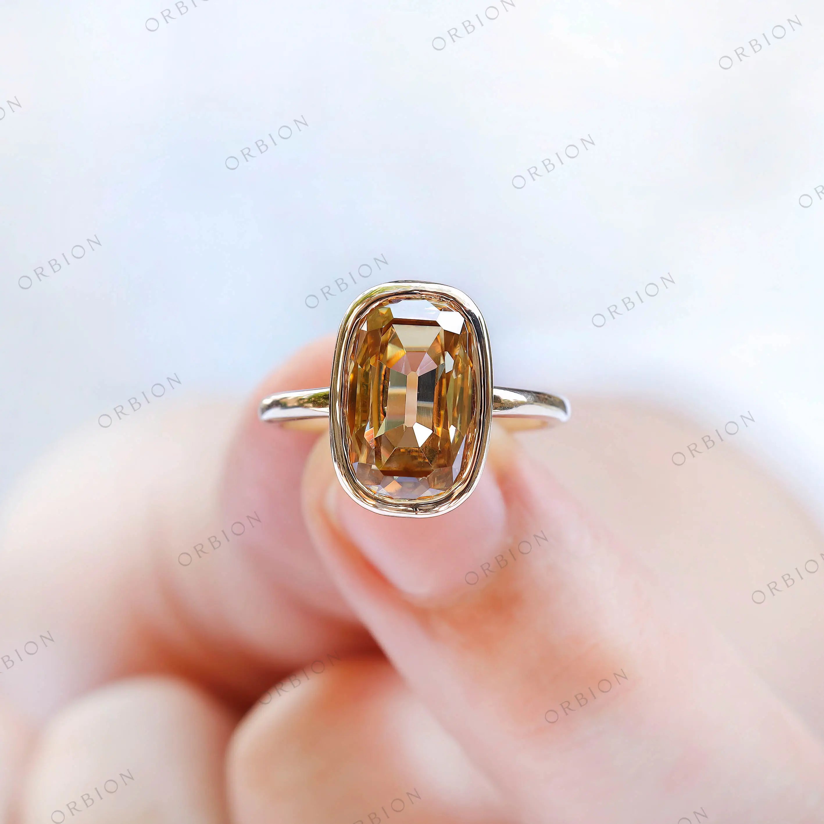 Close-up shot of elongated champagne moissanite ring on finger.