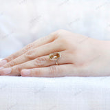 Elongated cushion champagne moissanite bezel ring in yellow gold worn on hand.
