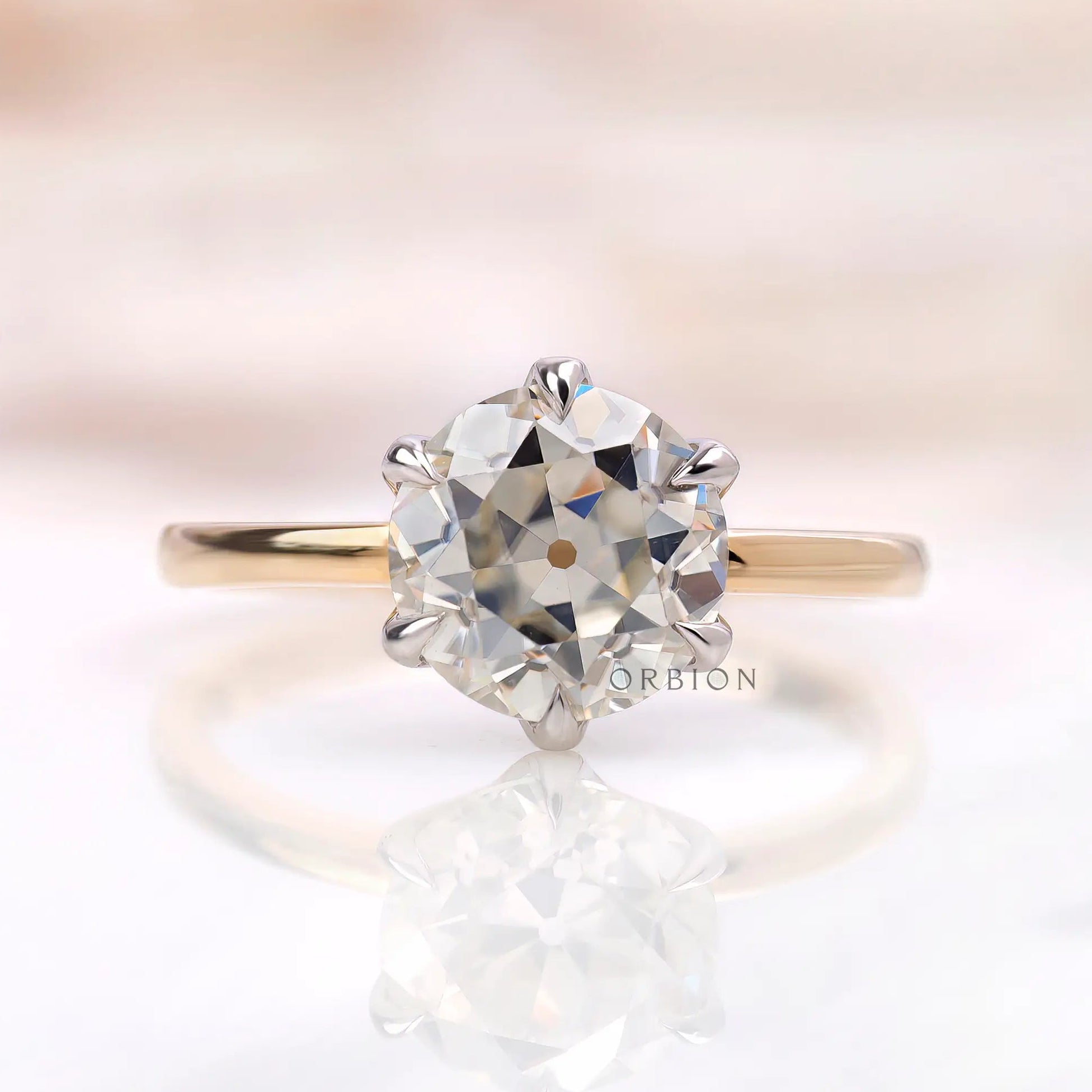 Front view of six prong solitaire OEC Moissanite ring in dual-tone gold.
