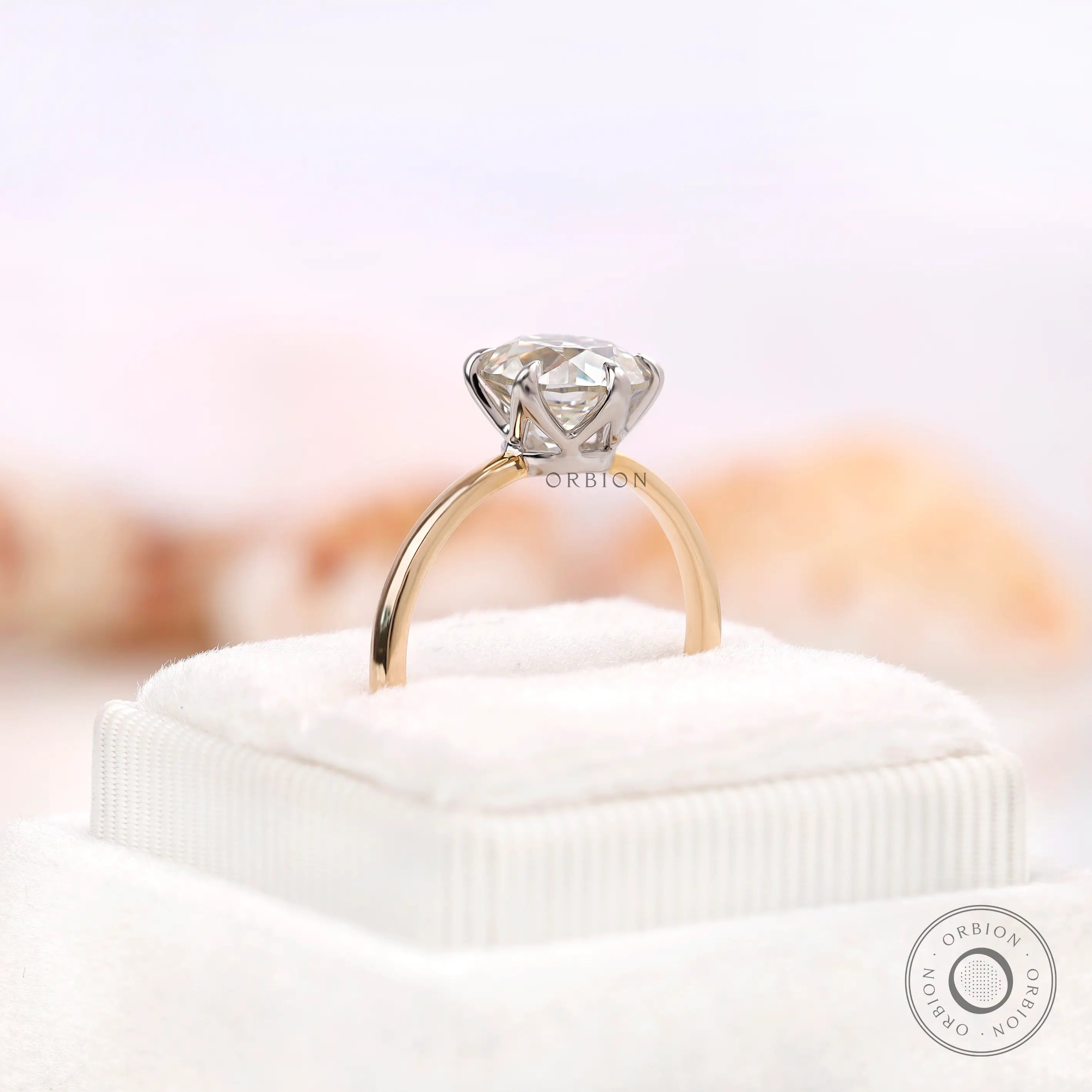Angled view of OEC Moissanite set in six-prong setting on box.