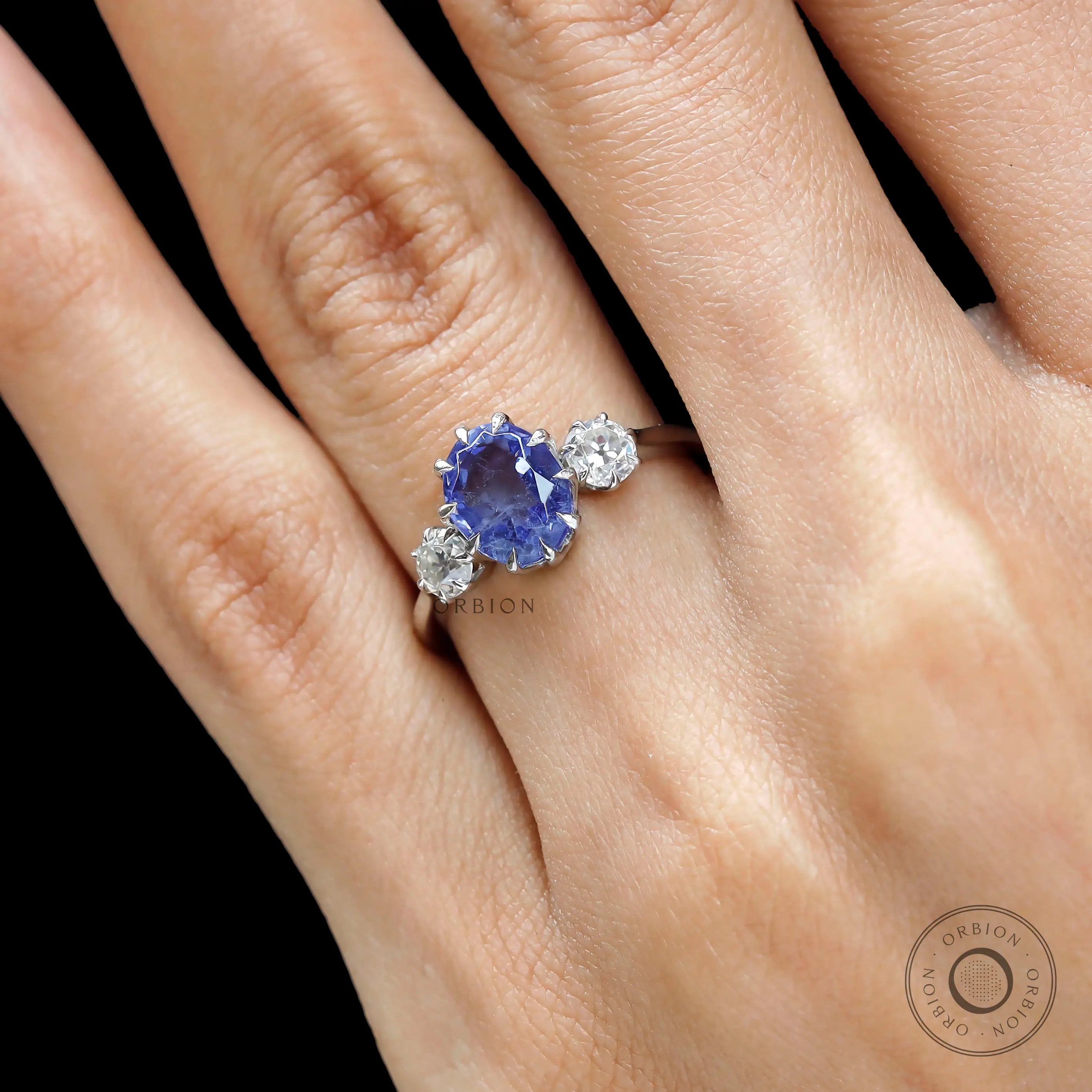 Close up of oval blue sapphire trilogy engagement ring