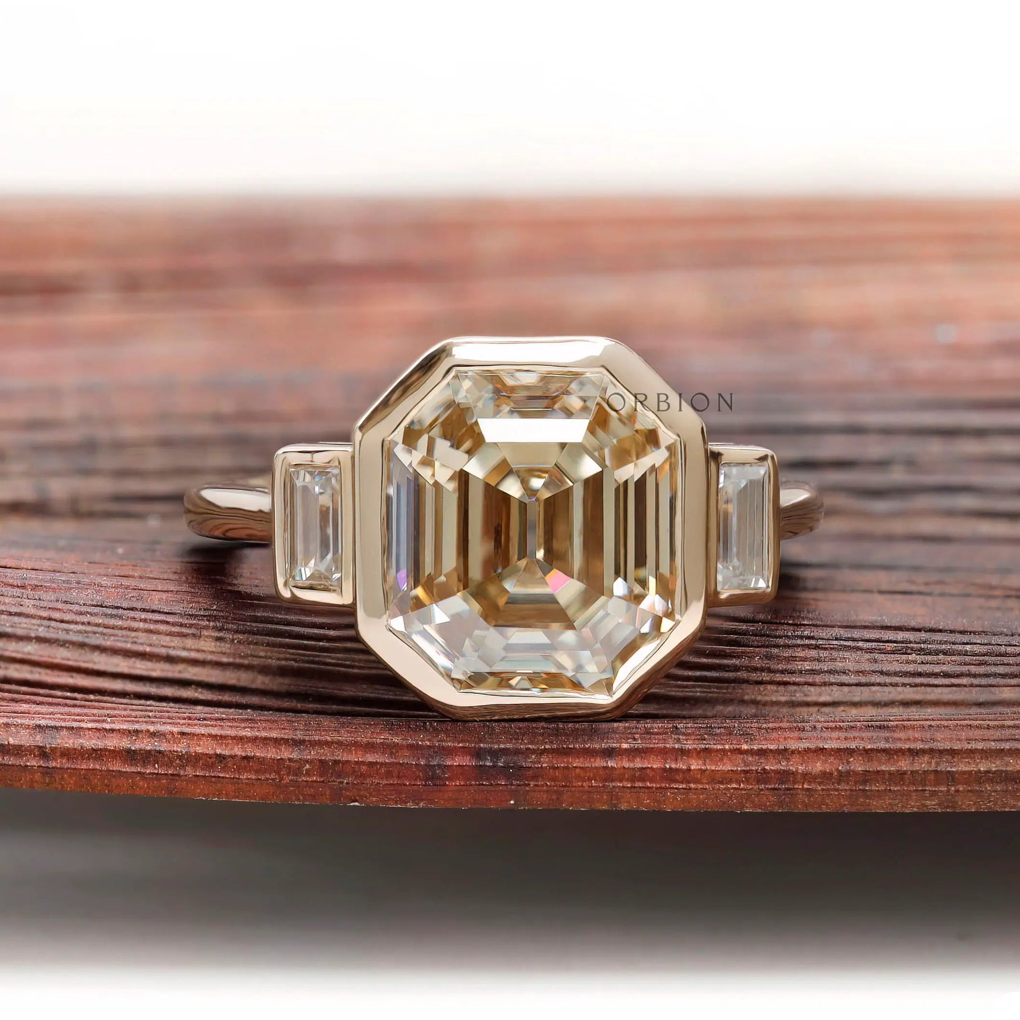 Emerald step cut light champagne moissanite bezel set engagement ring in yellow gold