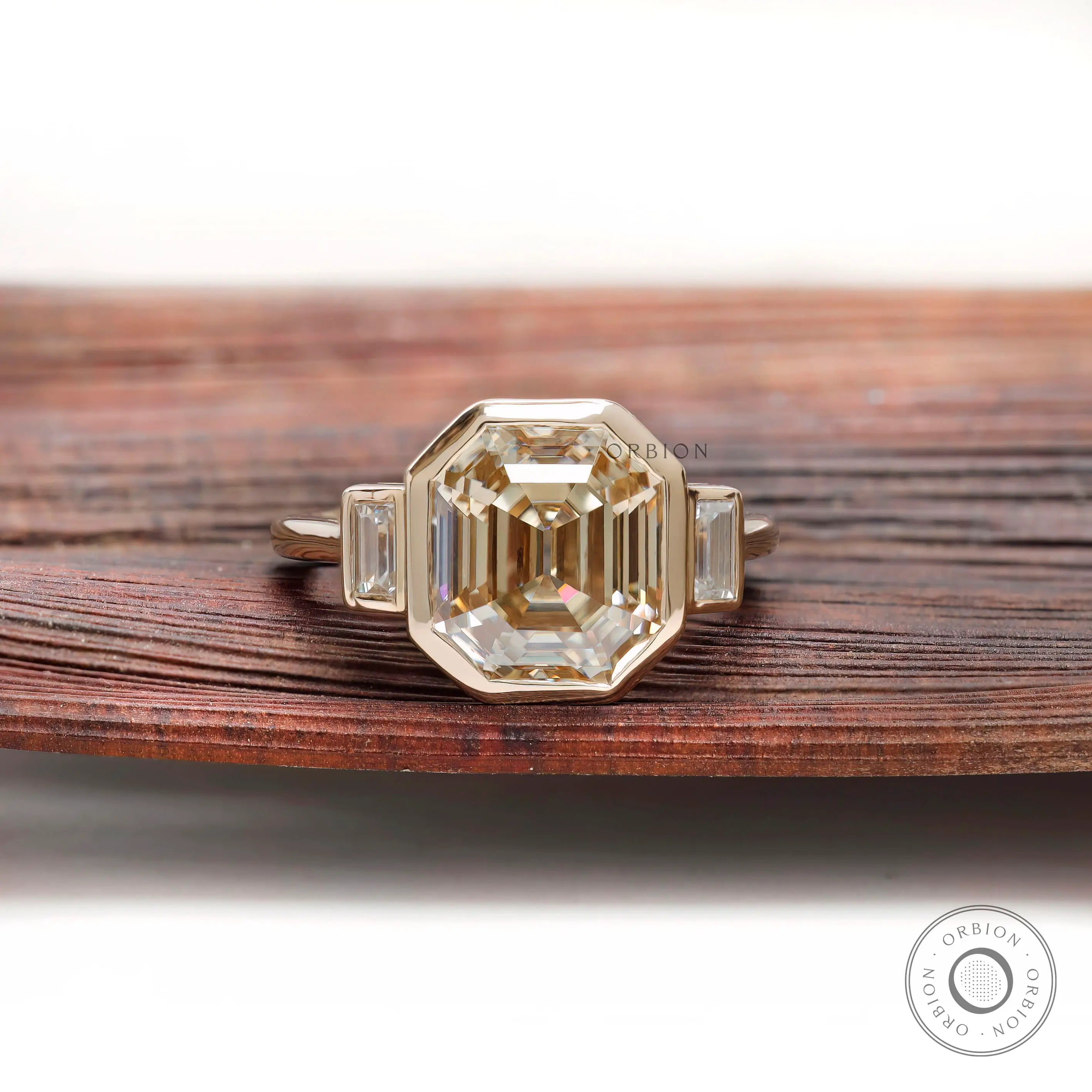 Emerald step cut light champagne moissanite bezel set engagement ring in yellow gold