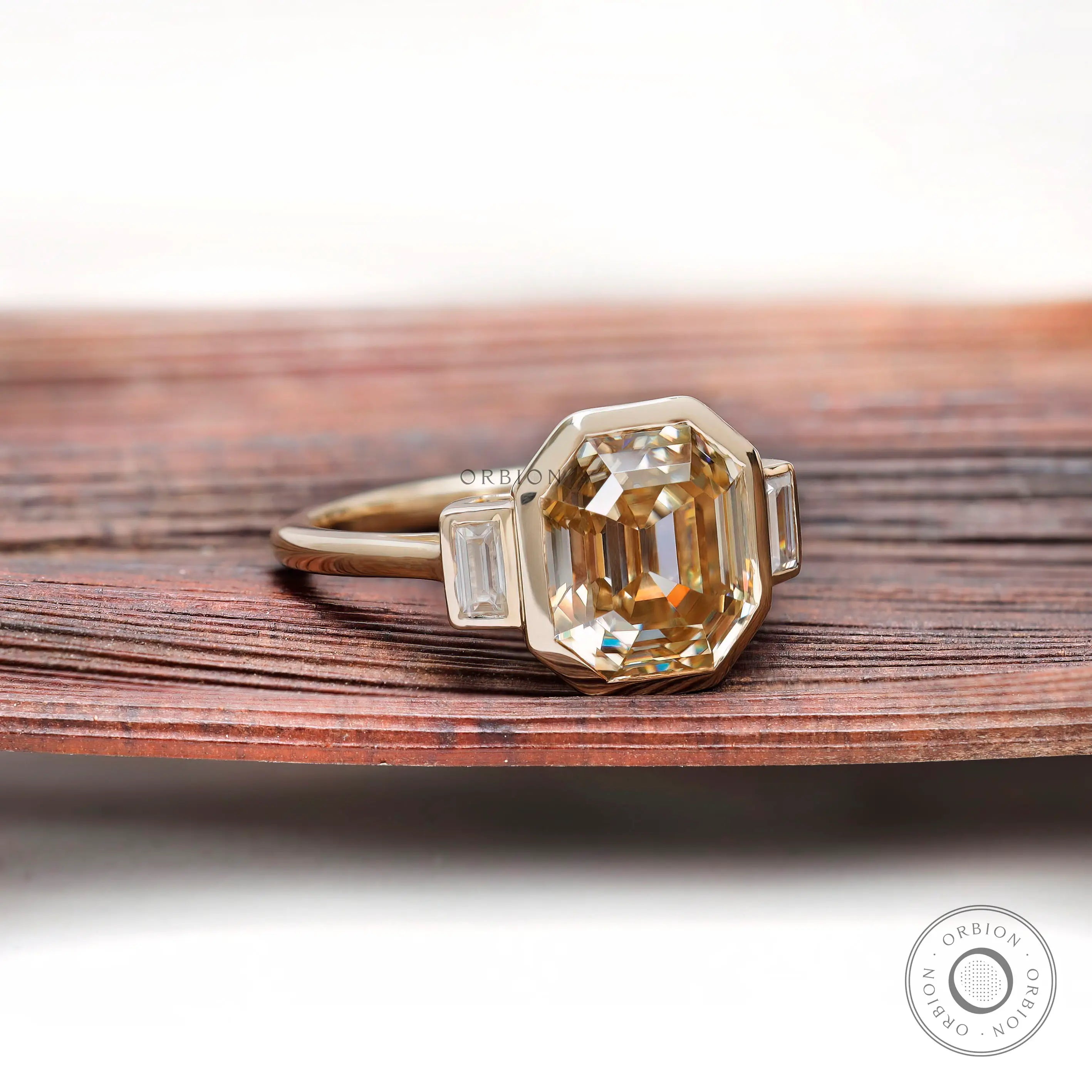 Bezel set emerald cut moissanite three stone ring with baguette sides