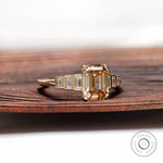 Close view of emerald cut champagne moissanite ring with tapered baguette accents