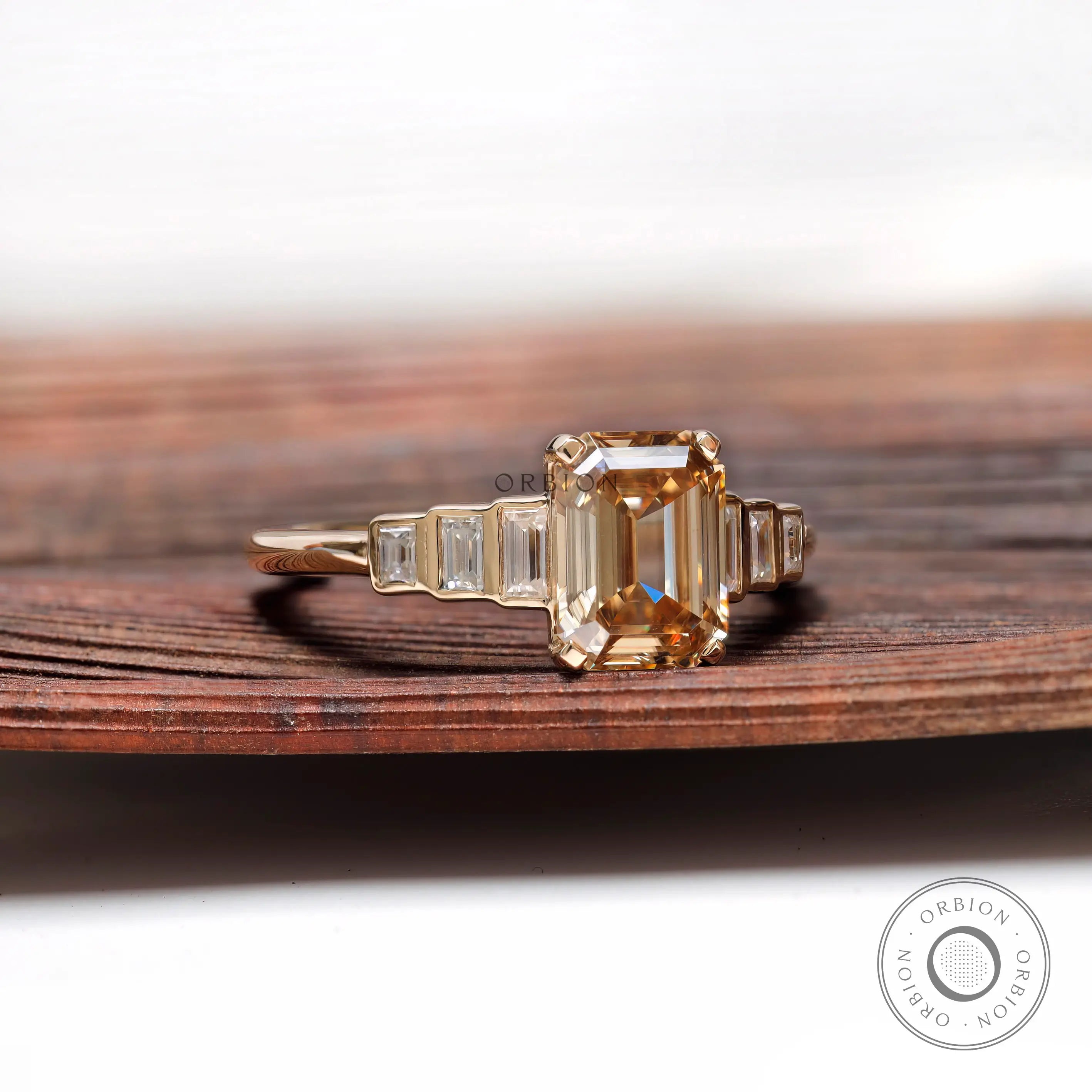 Close view of emerald cut champagne moissanite ring with tapered baguette accents