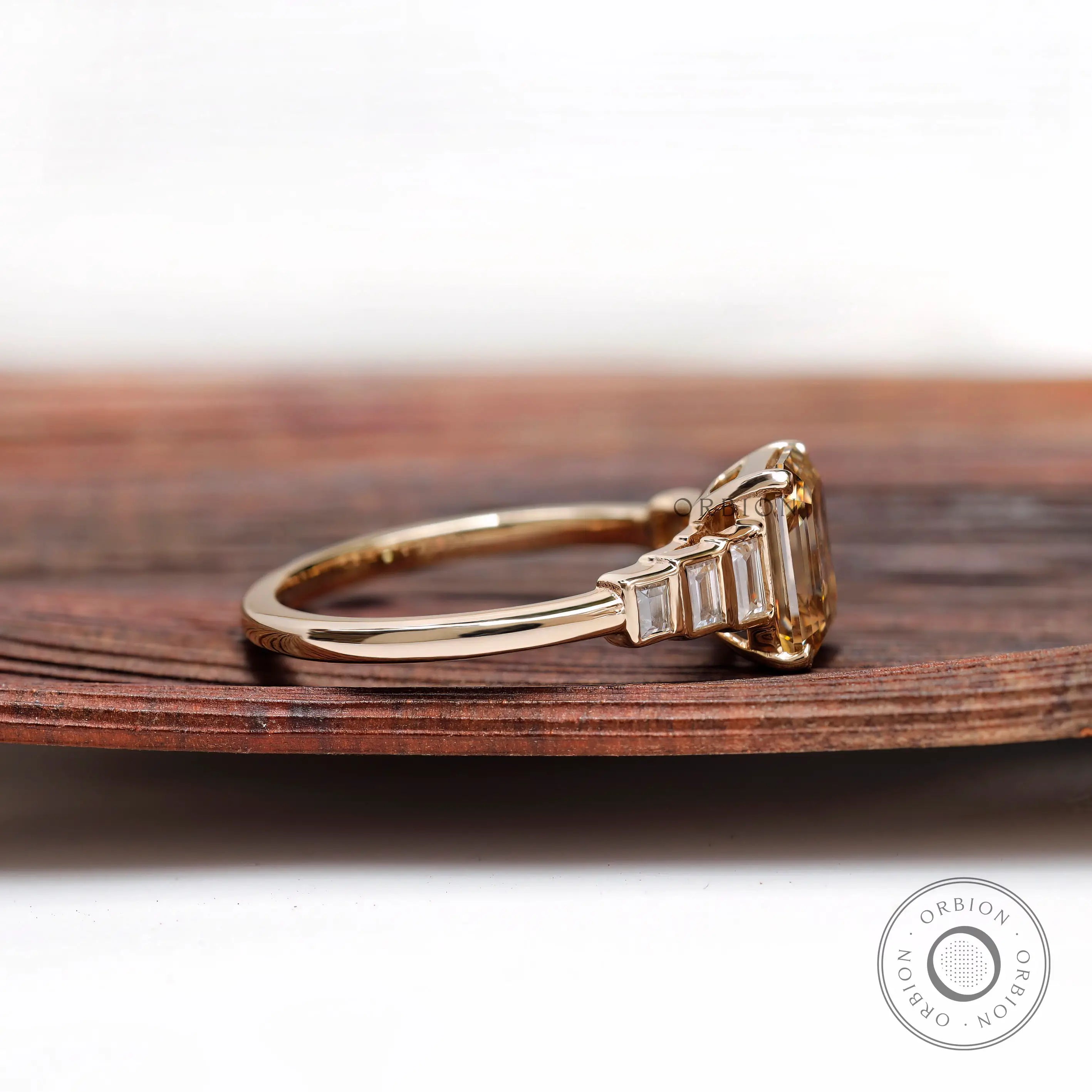 Side profile of emerald cut champagne moissanite ring with graduated baguette stones