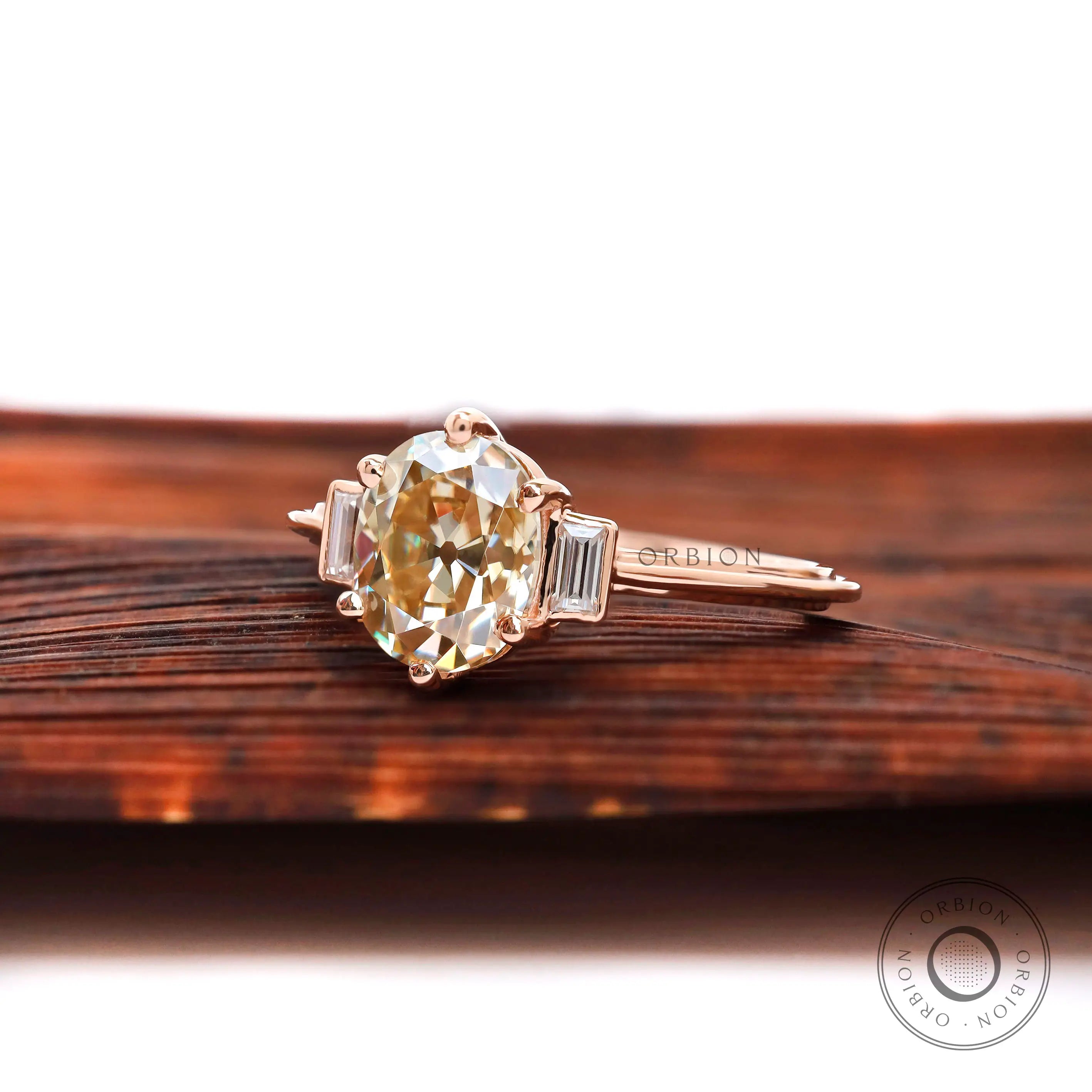 Angled view of champagne OEC Moissanite three-stone ring.