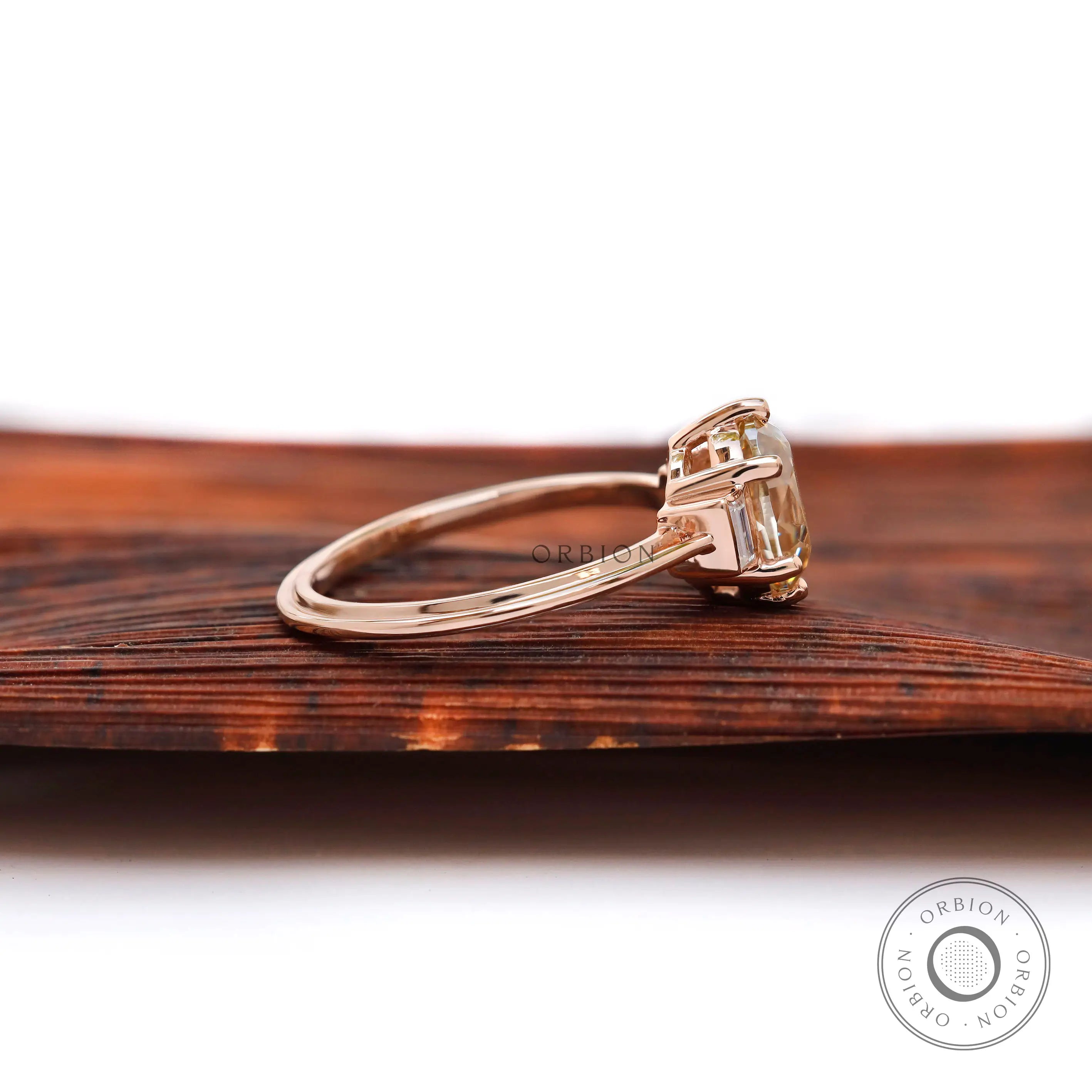 Side view of Champagne OEC Moissanite ring with baguette accents in rose gold.