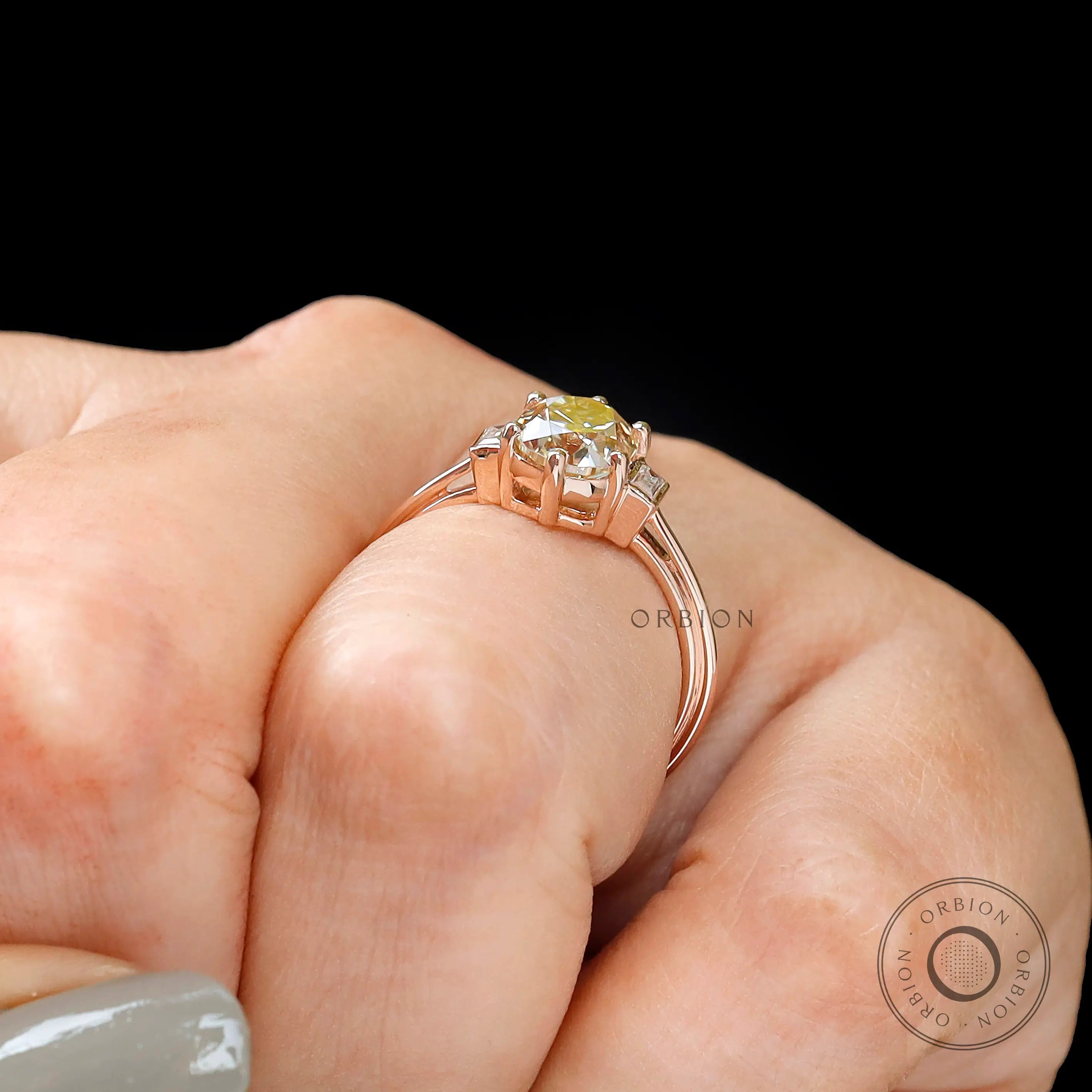 Close-up of hand with Champagne OEC Moissanite ring with baguette accents in rose gold