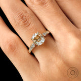 Moissanite engagement ring with an elongated cushion cut center stone, surrounded by round brilliant cut side stones in 18K yellow gold.
