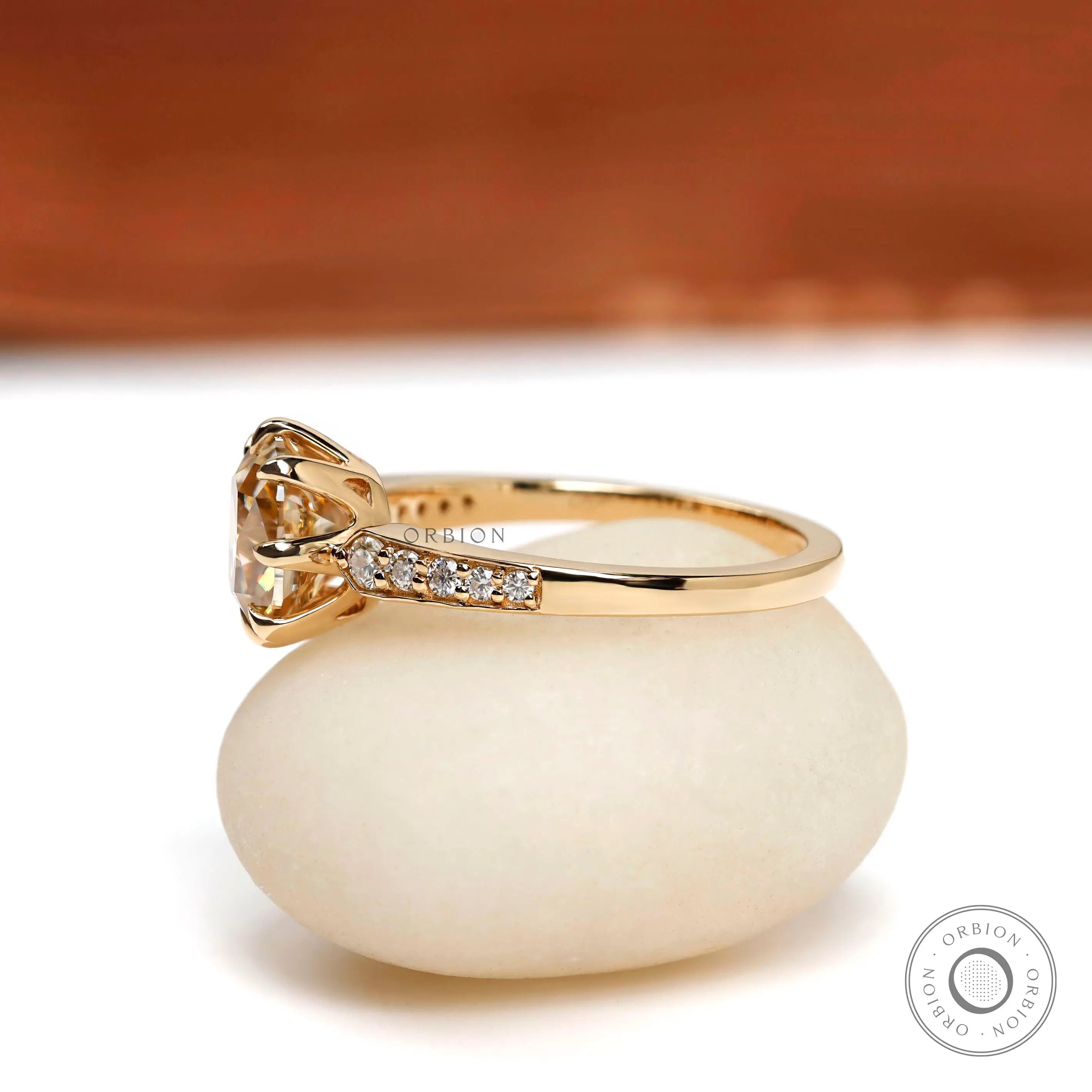 Side angle view of the elongated cushion Moissanite engagement ring in 18K yellow gold with brilliant round side stones.