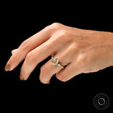 Moissanite engagement ring with elongated cushion cut center stone, designed with round side stones, showcased on a hand.