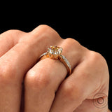 Close-up of the Moissanite engagement ring featuring an elongated cushion center stone and round brilliant side stones, held on a finger.