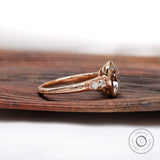Side view of the engagement ring with elongated cushion moissanite center stone and brilliant-cut side stones in 10K rose gold.