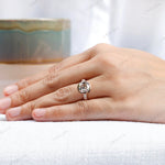 Hand model showcasing the 10K rose gold engagement ring with an elongated cushion moissanite center stone and side stones.