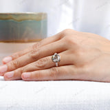 Hand model showcasing the 10K rose gold engagement ring with an elongated cushion moissanite center stone and side stones.