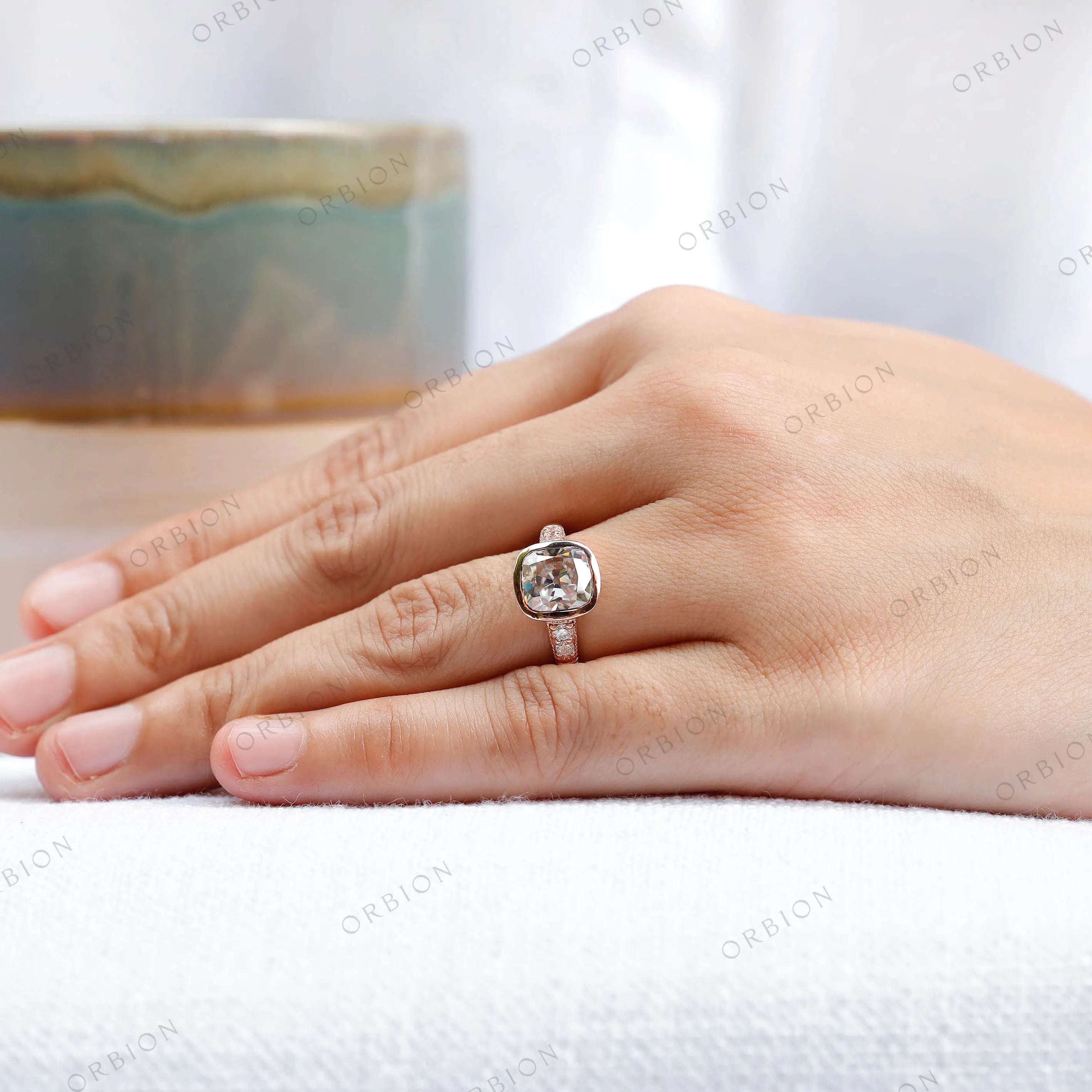 Hand model showcasing the 10K rose gold engagement ring with an elongated cushion moissanite center stone and side stones.
