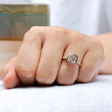 Ring shown on hand, featuring the elongated cushion moissanite center stone and round brilliant-cut side stones in 10K rose gold.