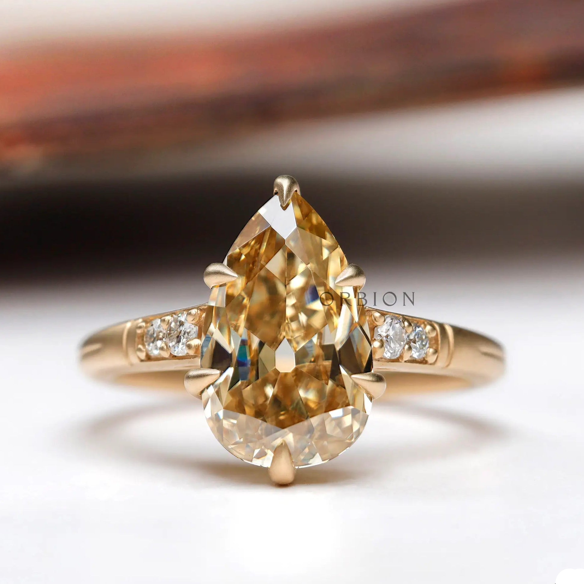 Pear cut light champagne moissanite ring in yellow gold front view