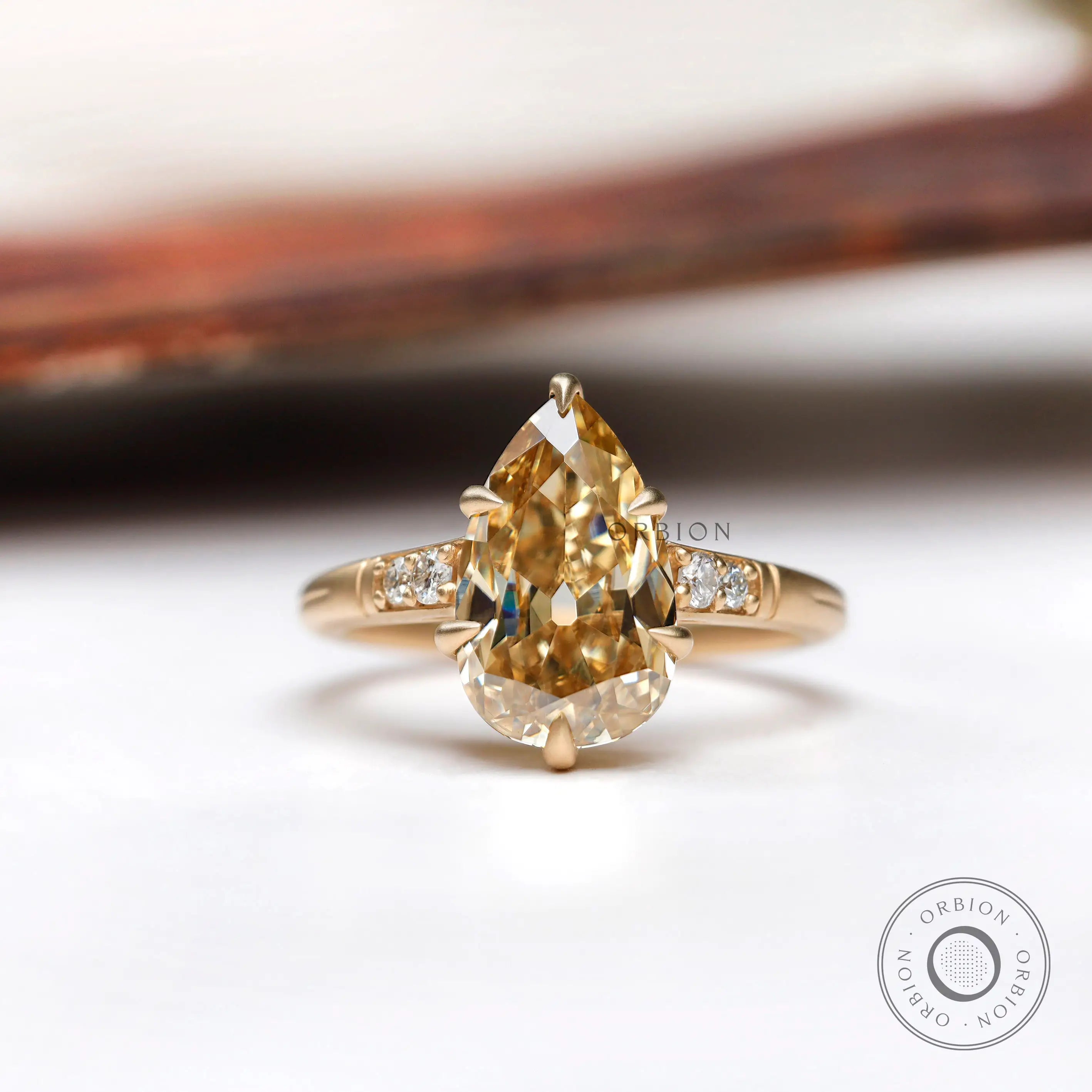 Pear cut light champagne moissanite ring in yellow gold front view