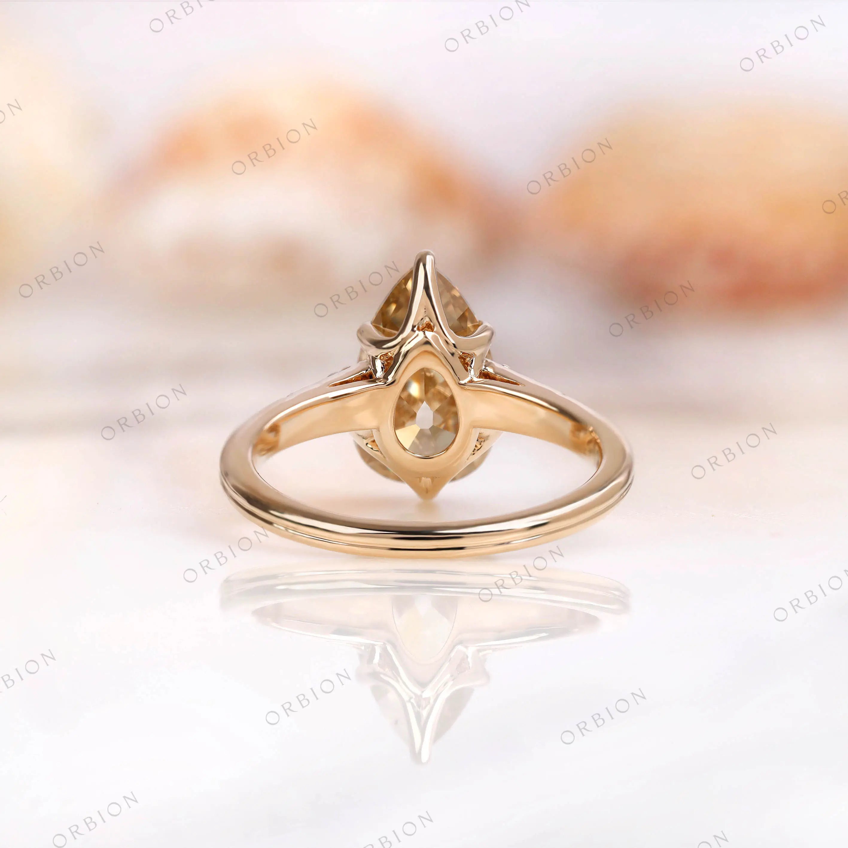 Back view of pear moissanite ring showing side profile and yellow gold band