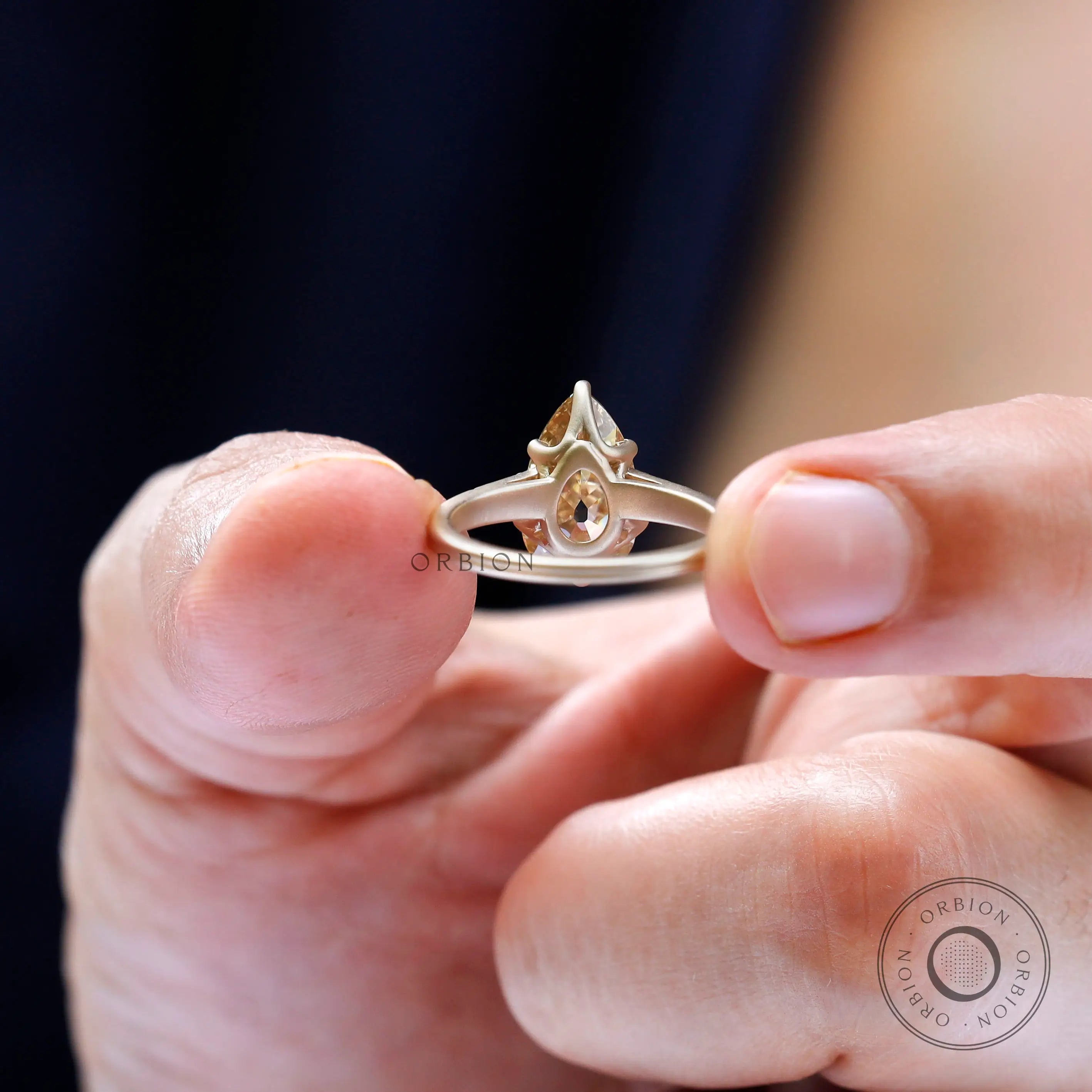 Round side stone detailing on pear moissanite engagement ring