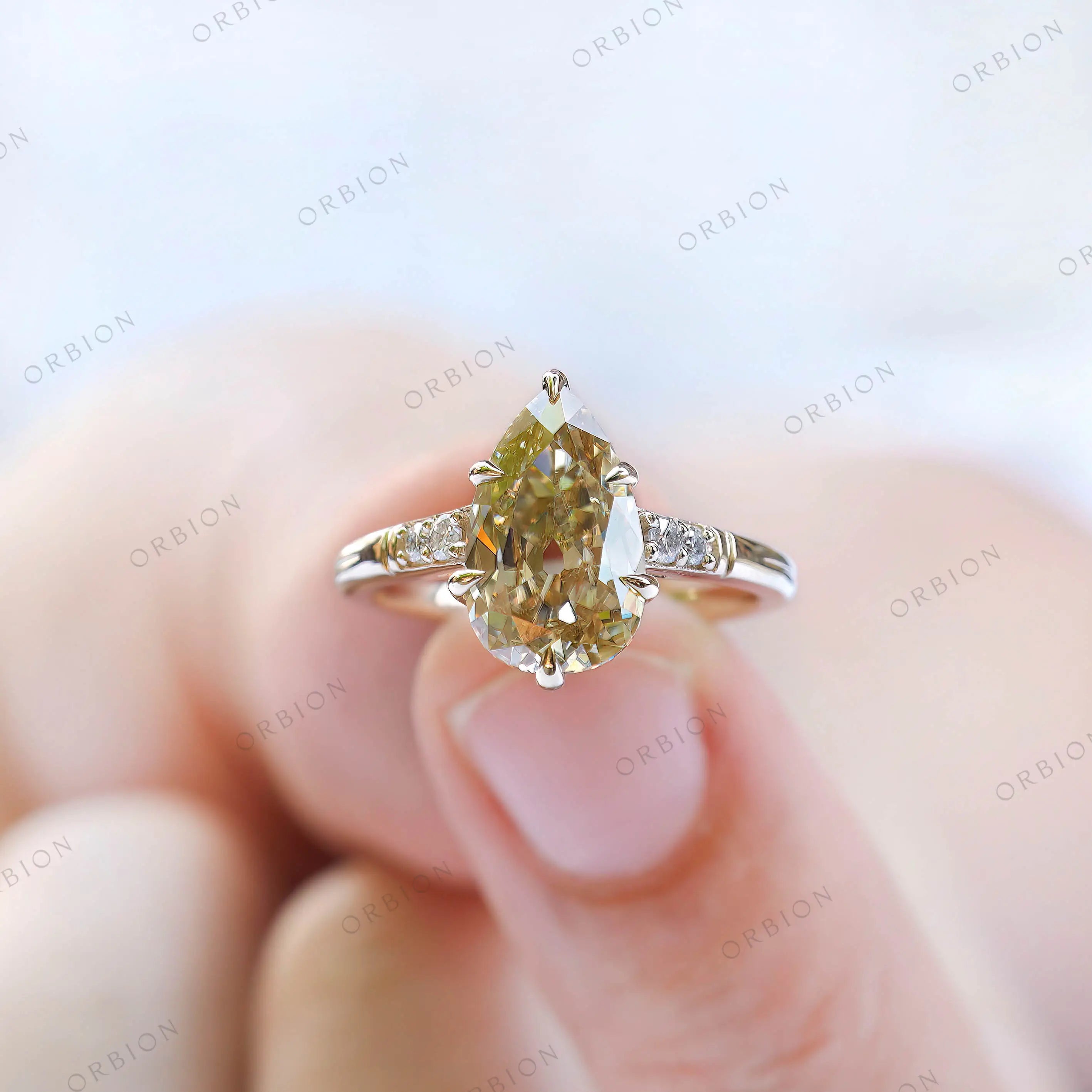 Person holding antique champagne moissanite pear ring