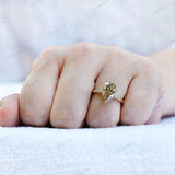 Close-up of antique champagne moissanite pear ring worn on finger