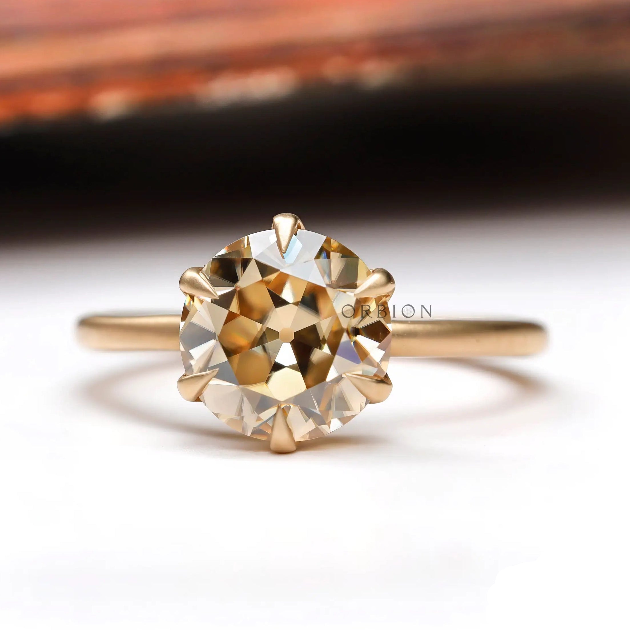 Elegant round Old European Cut light champagne moissanite solitaire engagement ring in 10K yellow gold.