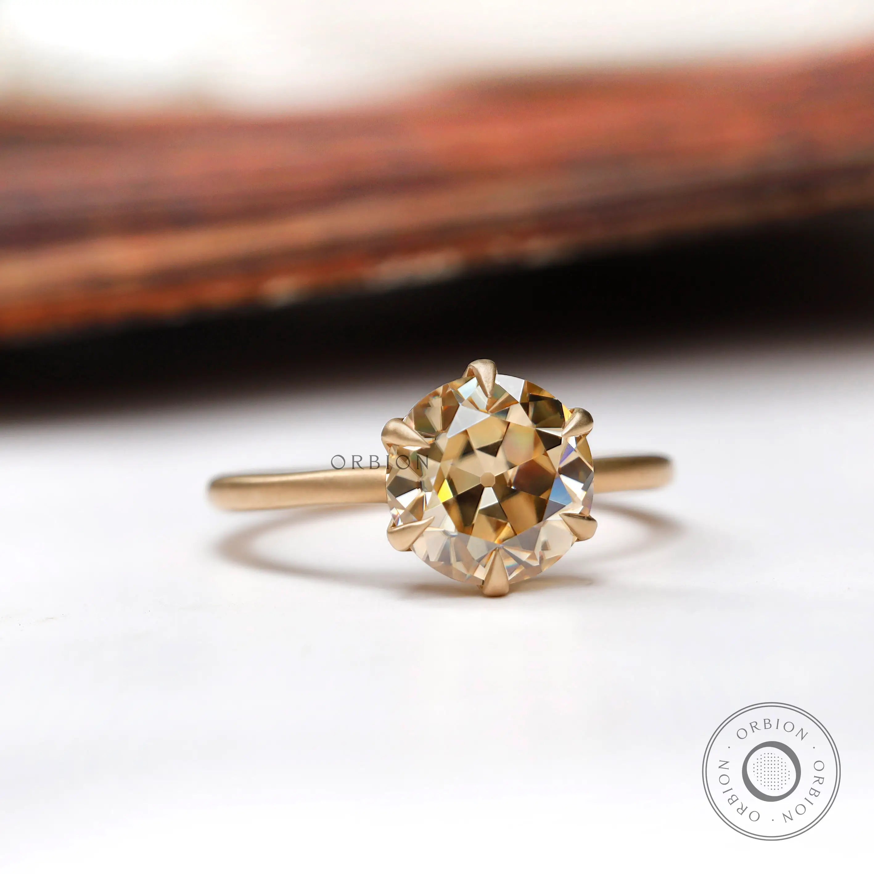 Angled side view of the round Old European Cut light champagne moissanite solitaire engagement ring in yellow gold.