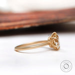Side profile showing the prong setting and high polish yellow gold band of the round moissanite engagement ring.
