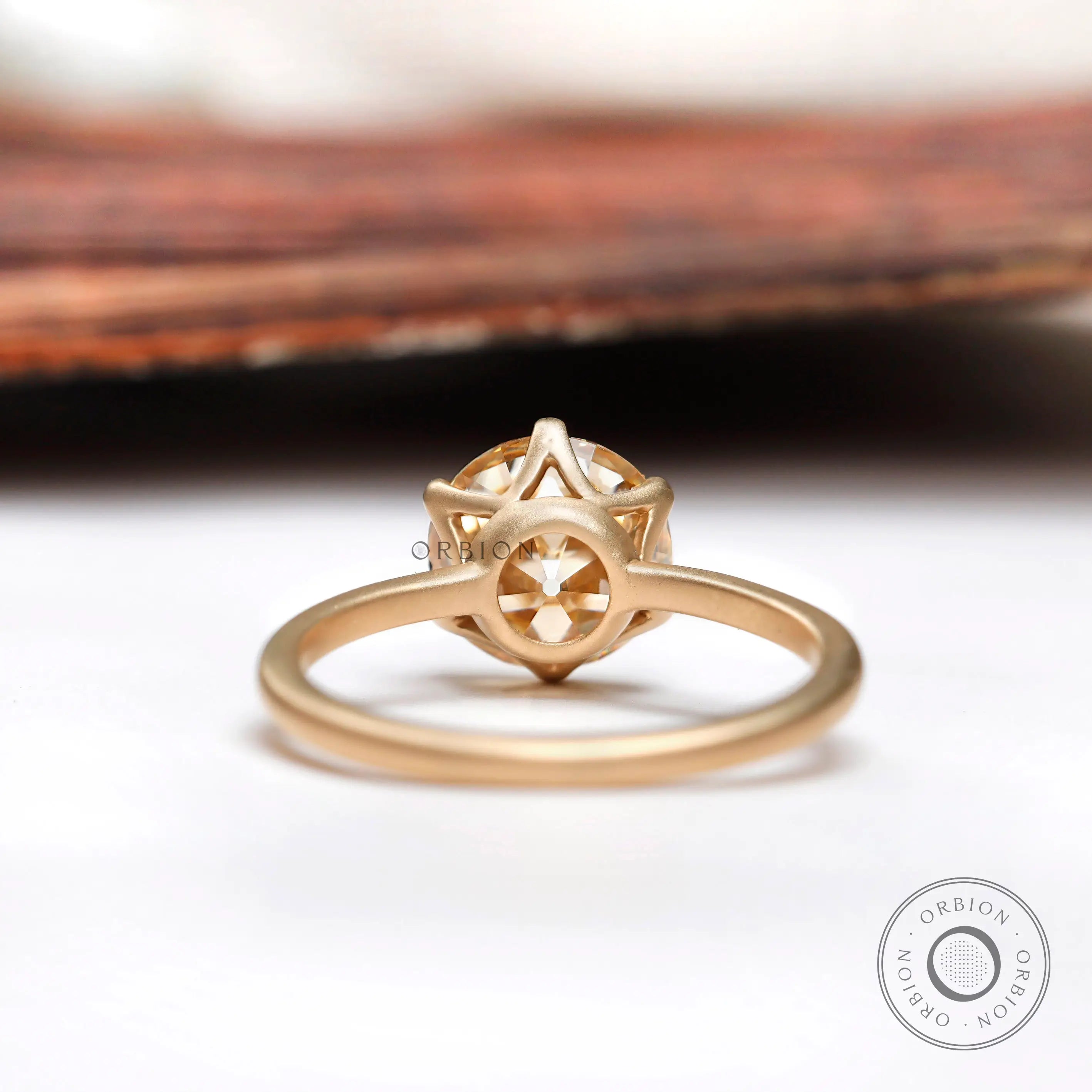 Back view of the round Old European Cut light champagne moissanite solitaire engagement ring in 10K yellow gold.