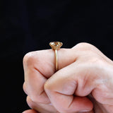 Solitaire round Old European Cut light champagne moissanite ring in 10K yellow gold worn on the finger.