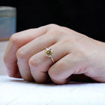 Solitaire round moissanite engagement ring in 10K yellow gold worn on hand.