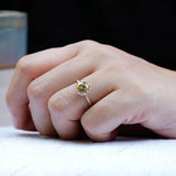 Solitaire round moissanite engagement ring in 10K yellow gold worn on hand.