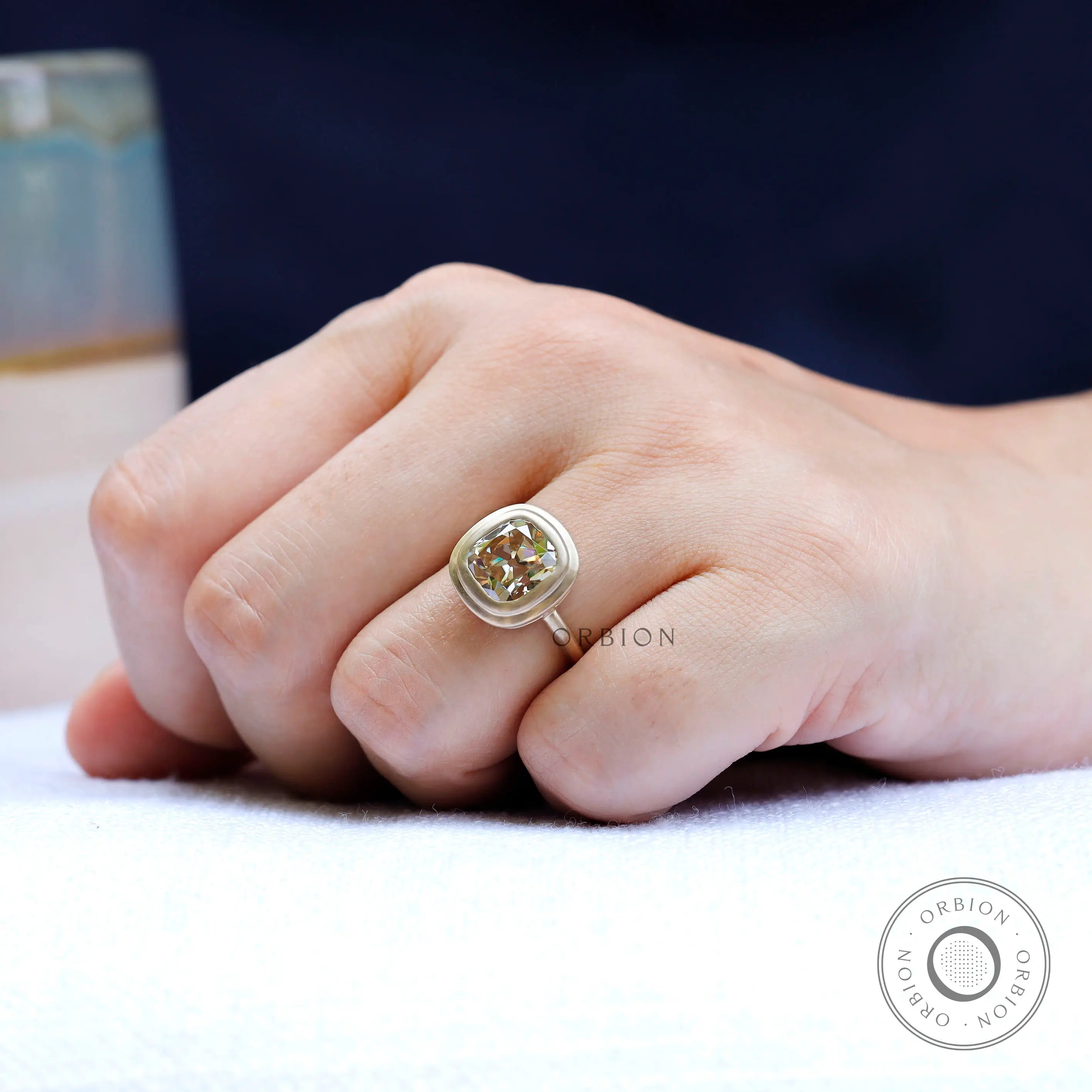 Contemporary matte finish bezel moissanite solitaire ring on finger