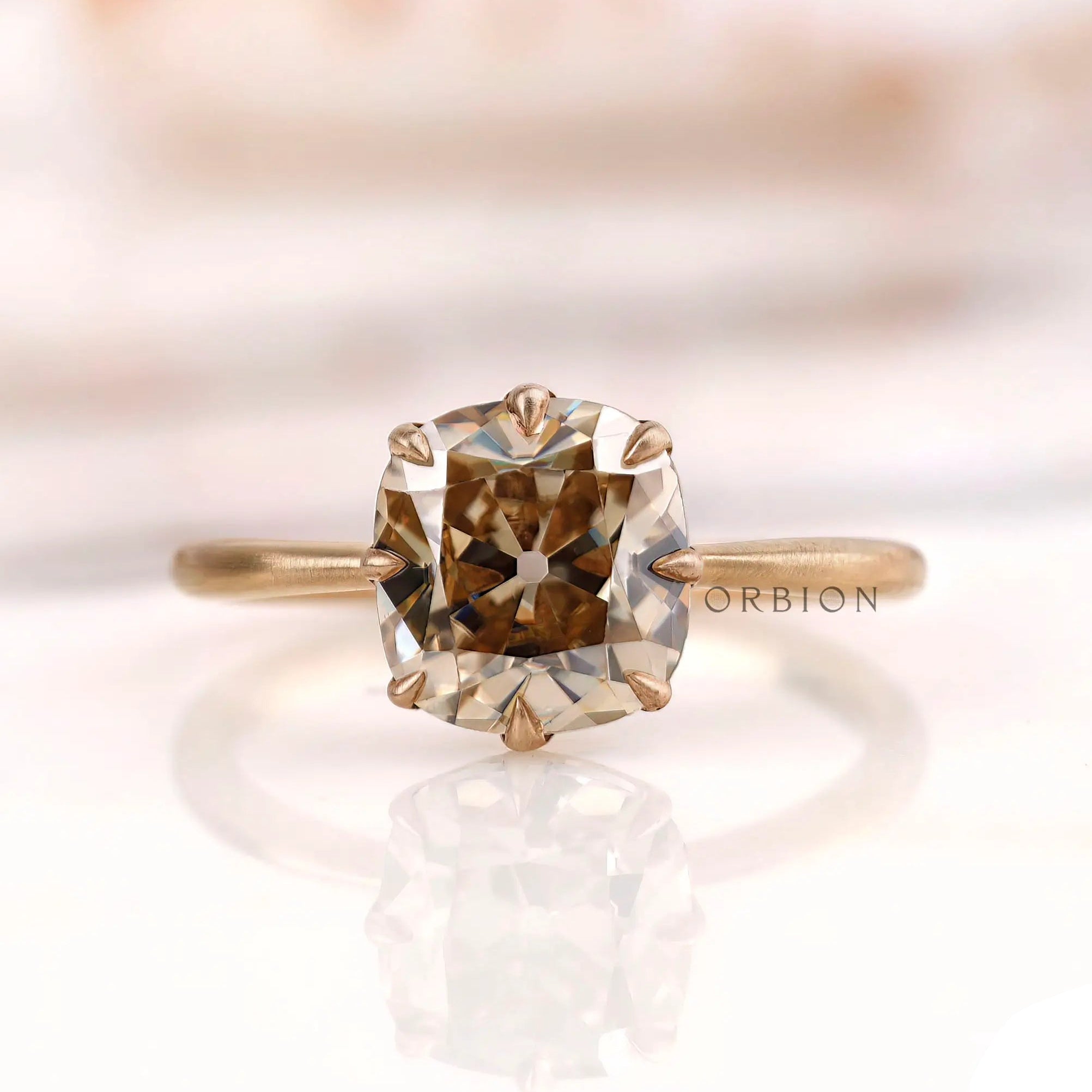 Front view of cushion champagne moissanite ring in matte finish yellow gold.