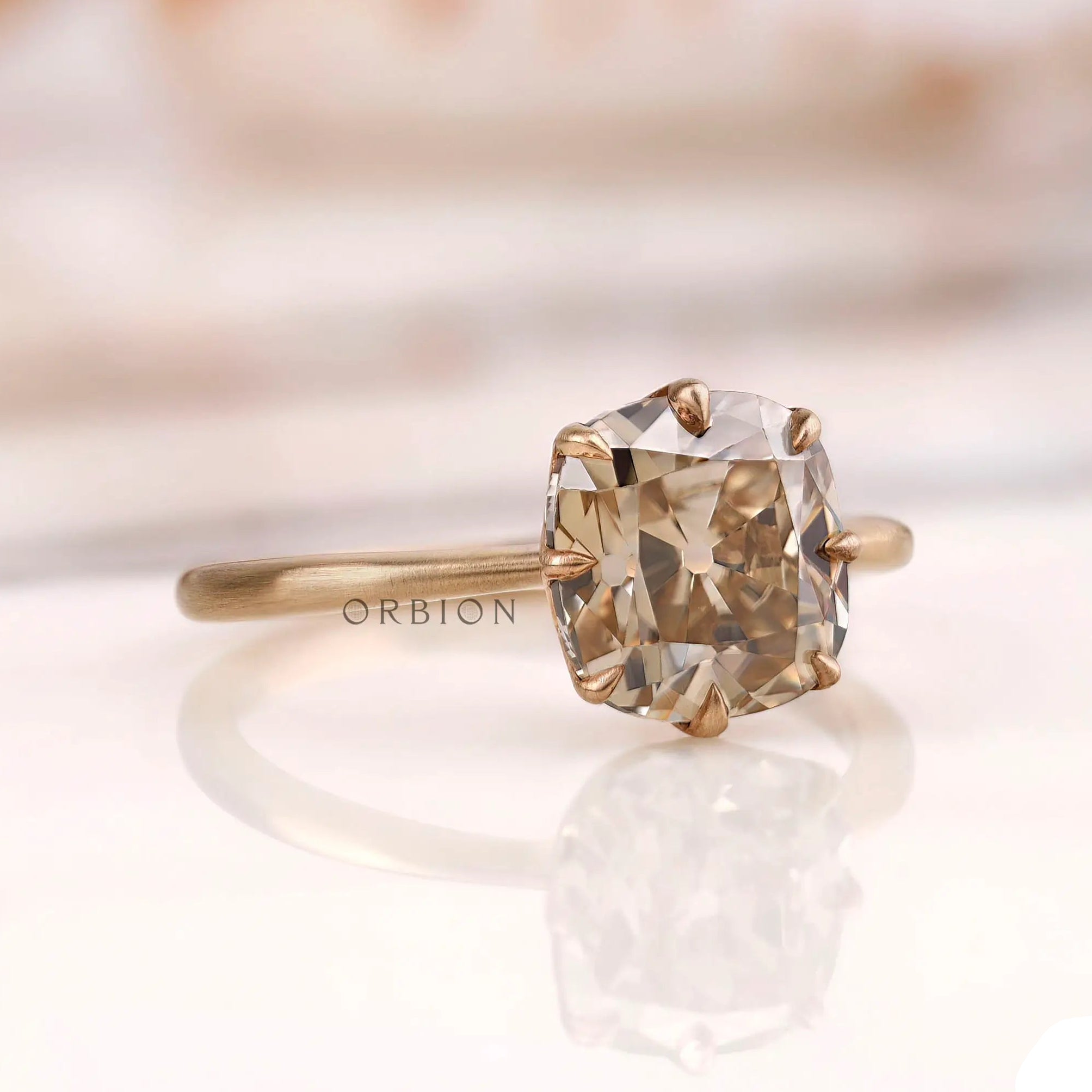 Angled side view of OMC cushion champagne moissanite solitaire ring.