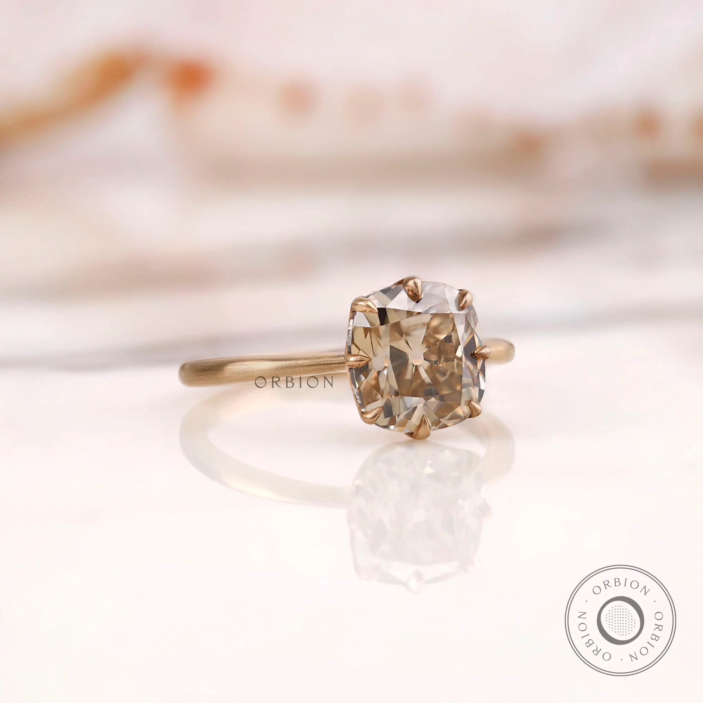 Angled side view of OMC cushion champagne moissanite solitaire ring.
