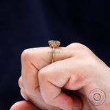 Hand wearing OMC cushion champagne moissanite solitaire ring, yellow gold band.