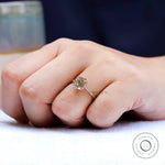 Side angle of hand with OMC cushion champagne moissanite solitaire ring in gold.