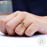 Side angle of hand with OMC cushion champagne moissanite solitaire ring in gold.