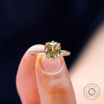 Close up view of solitaire ring held between the fingers.