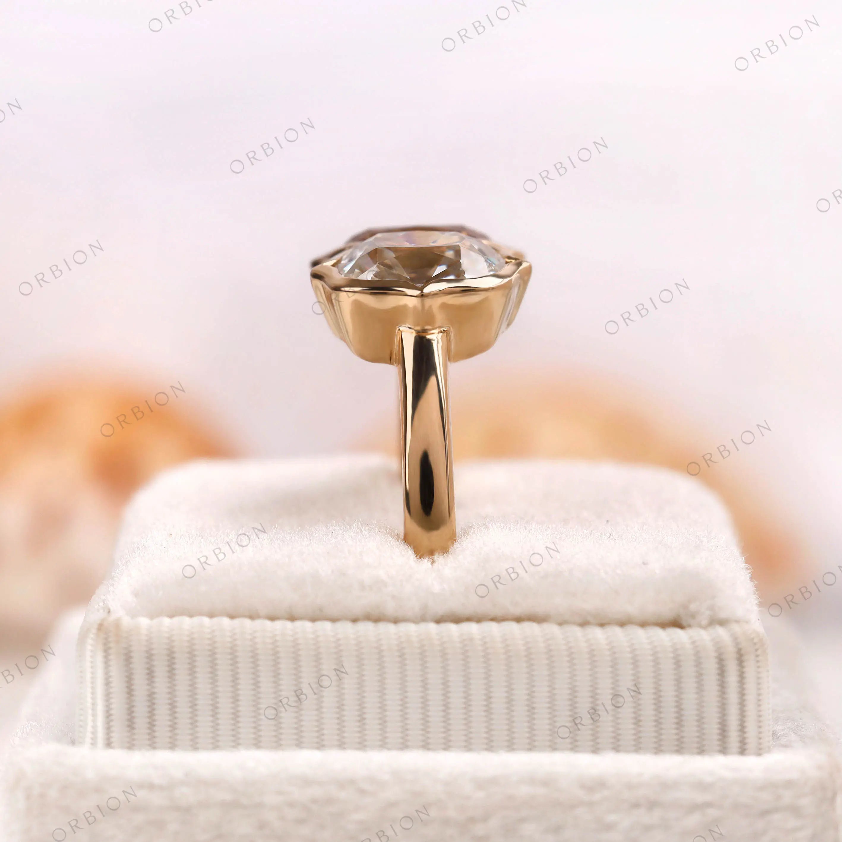 Close-up of champagne and D/E/F elongated cushion moissanites in bezel frames