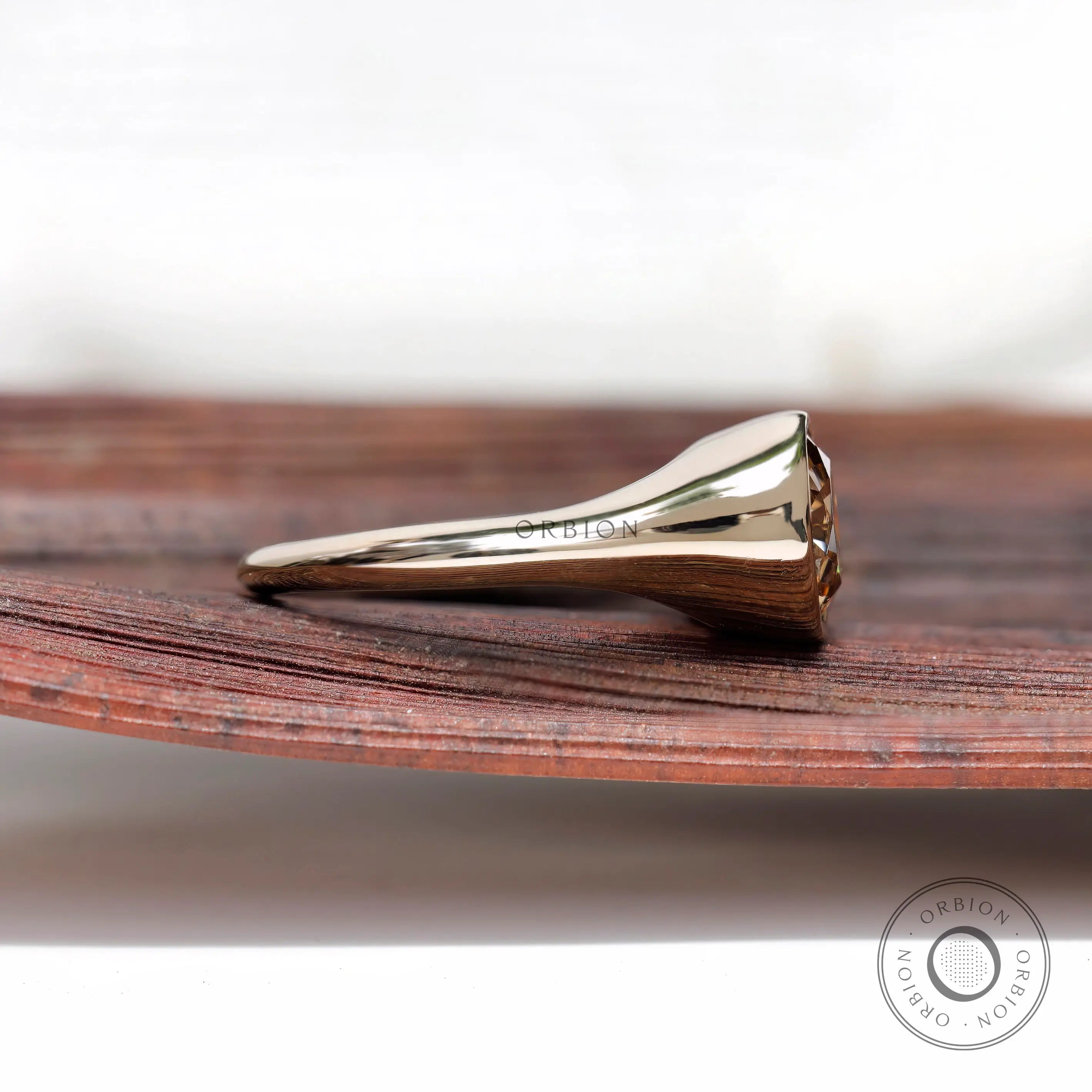 Side profile of bezel set solitaire moissanite signet ring in yellow gold