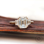 Three stone ring with trapezoid side stones in yellow gold