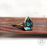 Front view of pear dark green moissanite bezel signet ring in yellow gold